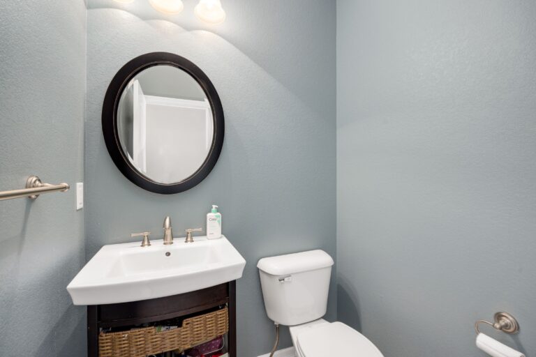 Compact half bath with a wall-hung basin, toilet and round mirror and no shower