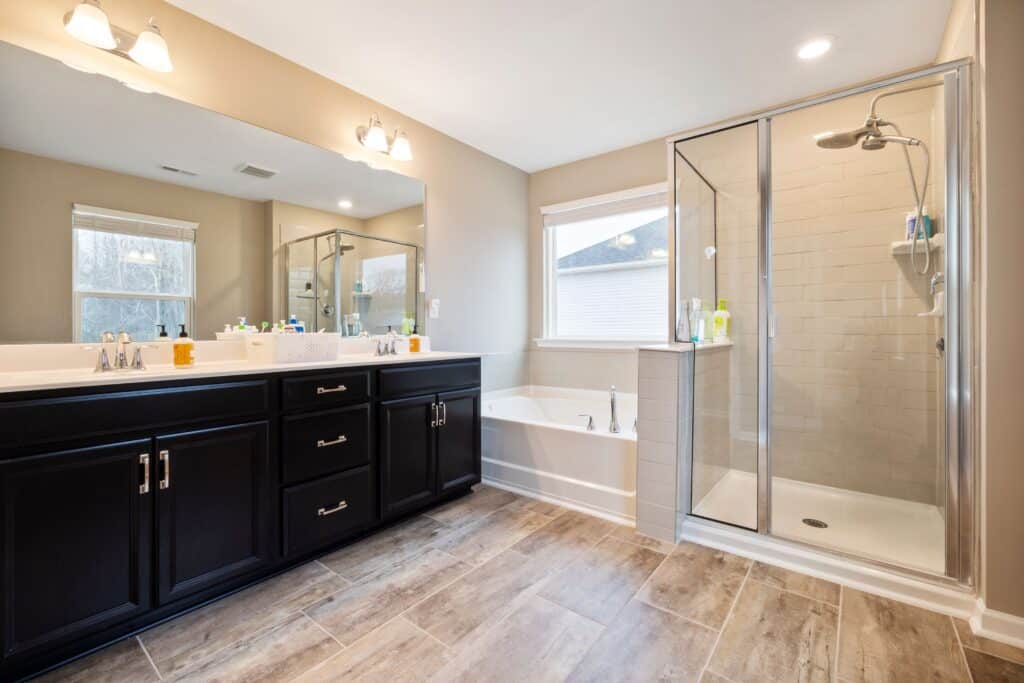 Completed bathroom remodel with a double vanity, glass-enclosed shower and natural light