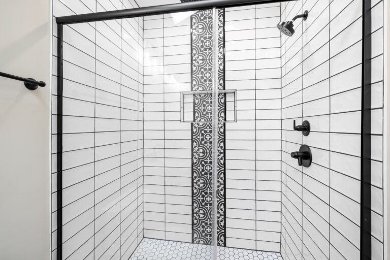 Remodeled shower with white subway tile, a vertical mosaic accent band and black framed glass