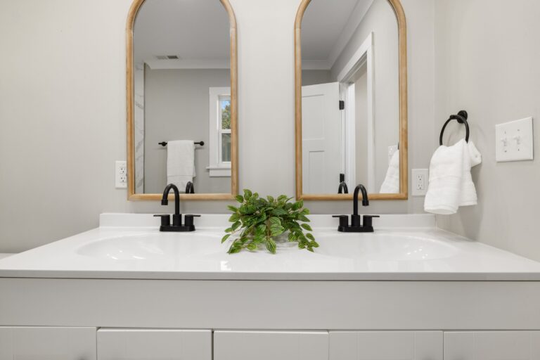 Master bathroom double vanity with stone countertop, twin basins, black faucets and framed mirrors