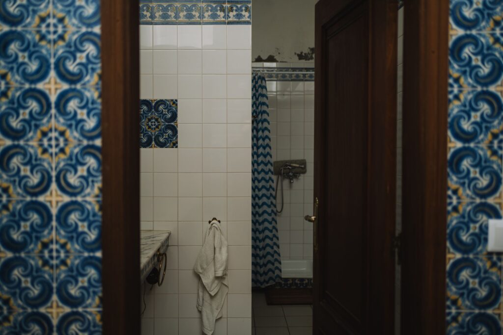 Dated bathroom with original blue and white patterned wall tile due for removal