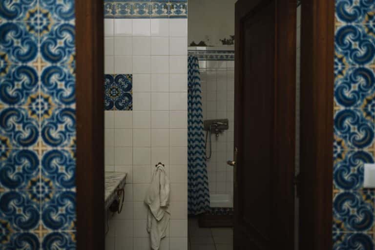Dated bathroom with original blue and white patterned wall tile due for removal