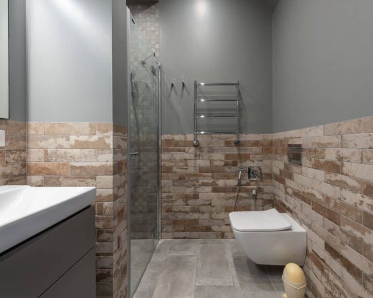 Retiled bathroom with stone-look wall tile, a glass shower enclosure and wall-hung toilet