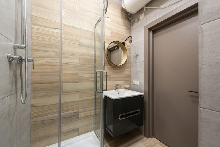Small bathroom made to feel larger with a clear glass shower enclosure, floating vanity and continuous wood-look tile