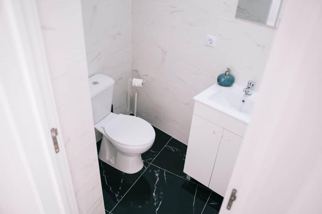 Compact remodeled bathroom with a slim vanity, toilet and dark marble-look floor tile