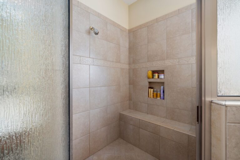Tiled walk-in shower with a built-in recessed niche, bench seat and frameless glass panel