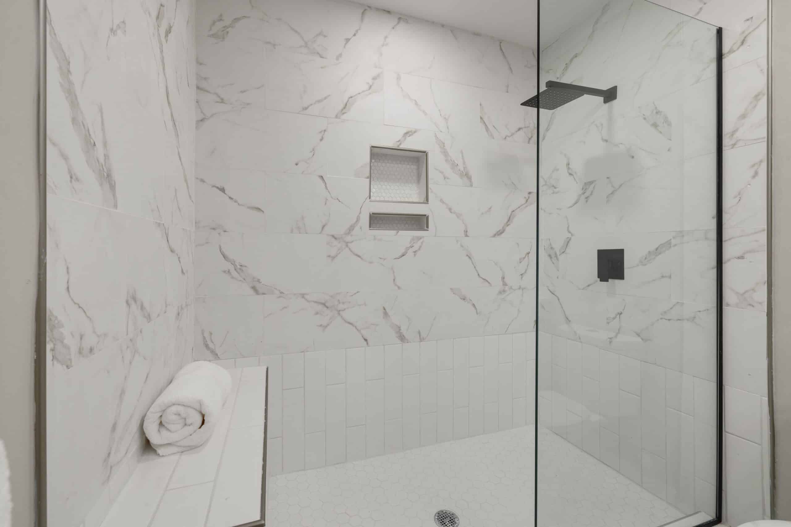 Walk-in shower with marble-look tile and glass panel installed in Freehold NJ by DK PRO Construction